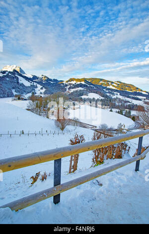 Paysage d'hiver pittoresque avec le village de montagne couverte de neige, le bleu ciel nuageux. District de Gruyère, Suisse Banque D'Images