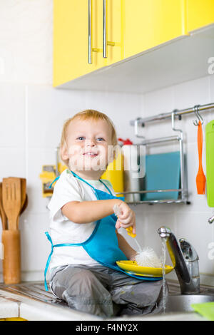 Kid boy lave-vaisselle et d'avoir du plaisir dans la cuisine Banque D'Images