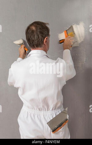 Travailleur manuel avec outils de plâtrage de mur à l'intérieur d'une chambre Banque D'Images