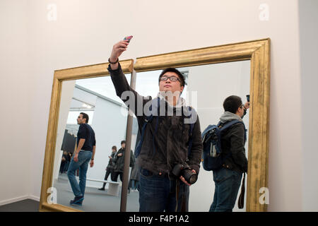 Frieze Art Fair de Londres. 2015. Un visiteur prend une en selfies face d'un miroir massive en deux moitiés. Banque D'Images