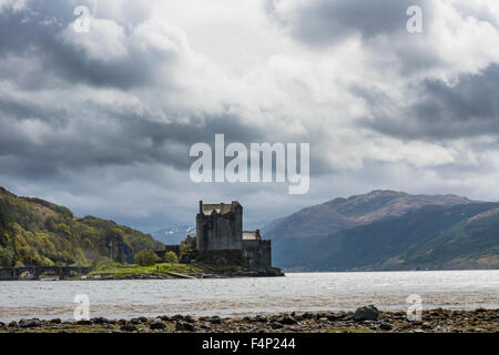 Eilean Donan Castle dans les Higlands écossais avec des nuages sombres, la lumière du soleil et l'océan. Banque D'Images