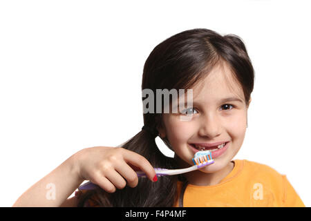 Peu de sept ans, montre un grand sourire montrant des dents manquantes avant haut et tenant une brosse à dents avec du dentifrice sur un livre blanc b Banque D'Images