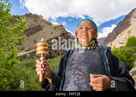 Une vieille femme ladakhis tourne une roue de prière dans une petite vallée au-dessus de hemis gompa Banque D'Images