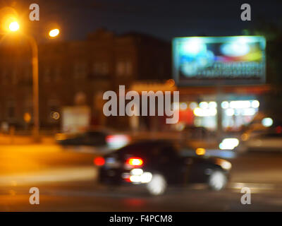 Abstract image floue d'une voiture roulant dans la ville avec l'éclairage de nuit et la lumière de l'enseigne au néon des panneaux publicitaires. Banque D'Images