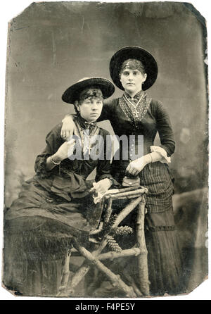 Portrait de deux femmes adultes, portant des chapeaux et des crucifix, tenant les mains, Tintype, vers 1870 Banque D'Images