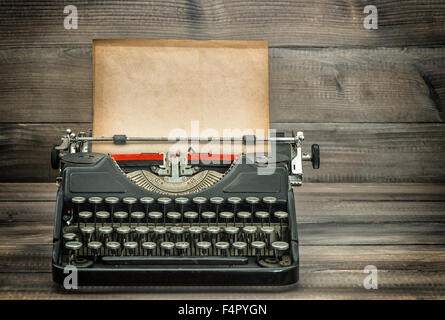 Machine à écrire antique avec grungy papier usé sur la page table en bois. Tons style vintage photo Banque D'Images