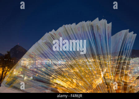 Cityscape at night avec Swiss francs billets près d'un lac avec vue sur la montagne et avec star trails à Lugano, Suisse. Banque D'Images