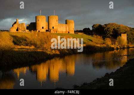 Le château de Rhuddlan au coucher du soleil, avec les nuages de tempête derrière et de réflexion dans la rivière Clwyd Banque D'Images