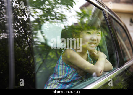 Heureuse petite fille assise dans la voiture Banque D'Images
