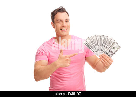 Jeune homme tenant une pile d'argent dans une main et pointant vers eux avec l'autre isolé sur fond blanc Banque D'Images