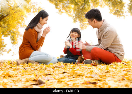 Des familles heureuses s'asseoir sur les feuilles et de jouer. Banque D'Images