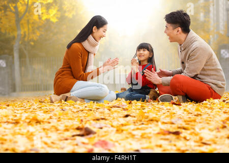 Des familles heureuses s'asseoir sur les feuilles et de jouer. Banque D'Images