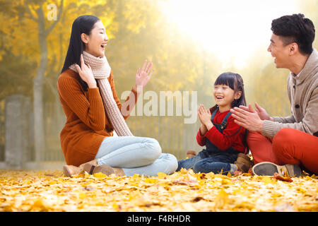 Des familles heureuses s'asseoir sur les feuilles et de jouer. Banque D'Images