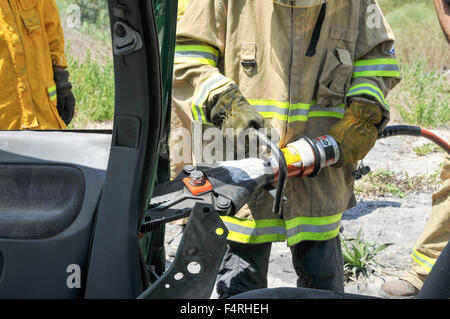 Les pompiers utilisent des outils pour sauver les passagers d'une voiture piégée Banque D'Images