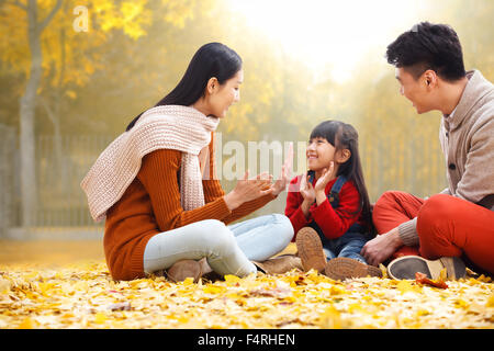 Des familles heureuses s'asseoir sur les feuilles et de jouer. Banque D'Images