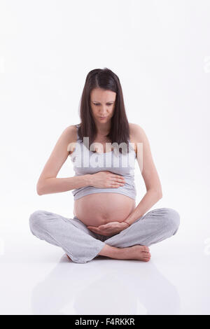 Femme enceinte en caressant son ventre sur fond blanc Banque D'Images