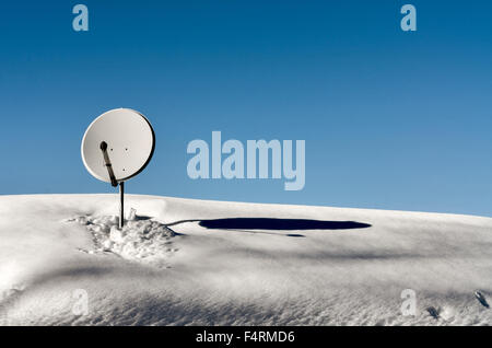 Plat satellite placé sur le toit de la maison de montagne couverte de neige Banque D'Images