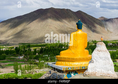 La statue du Bouddha d'or est situé sur une colline au-dessus de la vallée de l'indus, des champs verts et les hautes montagnes au loin Banque D'Images