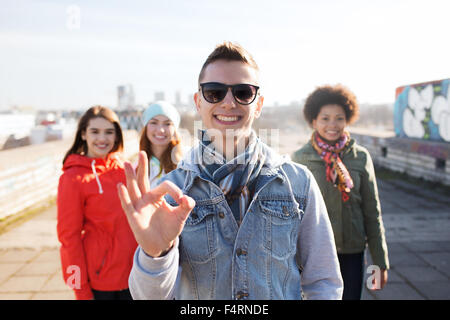 Teenage friends showing ok sign on street Banque D'Images