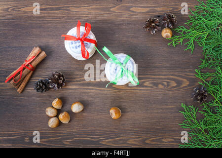 Les biscuits de Noël avec des rubans, pommes, noix, pommes de pin, la cannelle et le thuya vert direction sur une table en bois. Banque D'Images