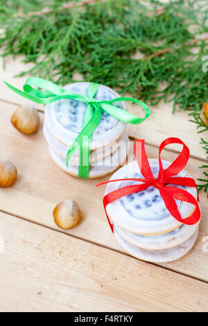 Les biscuits de Noël avec des rubans, pommes, noix, pommes de pin, la cannelle et le thuya vert direction sur une table en bois. Banque D'Images