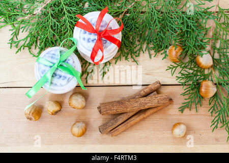 Les biscuits de Noël avec des rubans, pommes, noix, pommes de pin, la cannelle et le thuya vert direction sur une table en bois. Banque D'Images