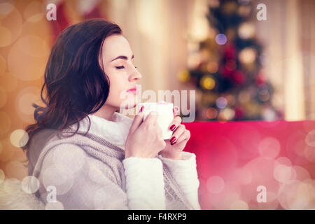 Image composite de brunette prenant un chocolat chaud à Noël Banque D'Images