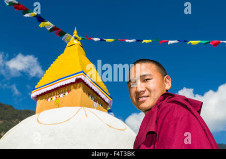 Portrait d'un jeune moine tibétain, stupa blanc avec drapeaux de prière à l'arrière Banque D'Images