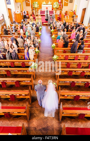 Un père conduit sa fille dans l'allée à son mariage Banque D'Images