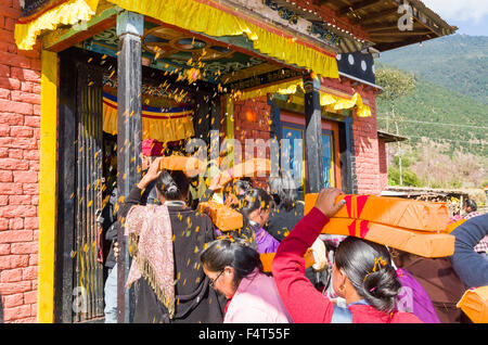 Gens portant des livres de prière tibétain, enveloppé dans matériau jaune, sur leurs têtes à Lhapab Tuchen festival. Banque D'Images