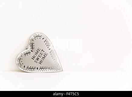Tin coeur contre mur blanc Banque D'Images