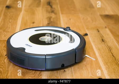 Un aspirateur robot iRobot Roomba le nettoyage d'un sol en bois Banque D'Images