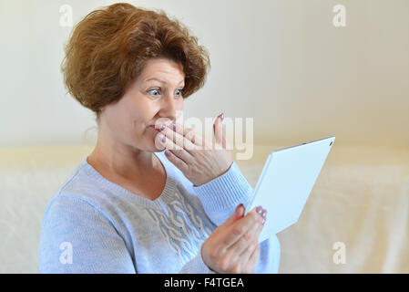 Femme dans l'étonnement à la tablette à l'ordinateur Banque D'Images