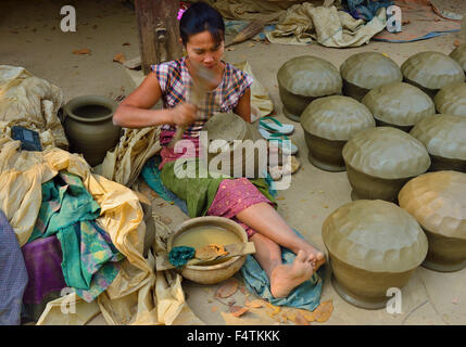 Femme dans l'Irrawaddy Yandabo village près de Mandalay devançant ces vases en argile en forme avec une palette de bois . Banque D'Images