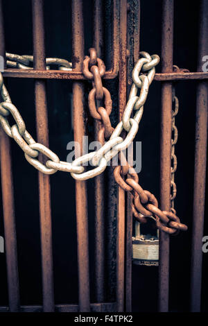 Moody concept métal rouillé portes sont verrouillées par des liens avec l'ancienne chaîne de patine autour de barres de fer symbolisant pas de s'échapper ou d'entrée Banque D'Images