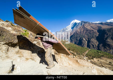 Porter porter de lourds à charger une voie ascendante au-dessus de Namche Bazar (3,440 m), la base pour le trekking et l'alpinisme en solo Banque D'Images