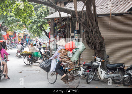 Scène de rue à Hanoi, dame riding bicycle carrying cardboard,Vietnam,Asia Banque D'Images