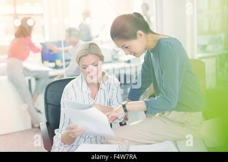 Businesswomen discussing paperwork in office Banque D'Images