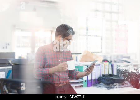 Designer de mode de boire du café using digital tablet in office Banque D'Images