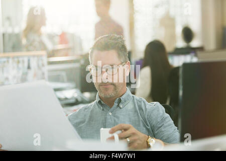 Créateur de mode de l'examen de documents et de boire du café in office Banque D'Images