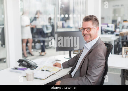 Portrait confident businessman at desk in office Banque D'Images