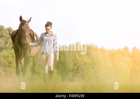 Woman walking horse in rural field Banque D'Images