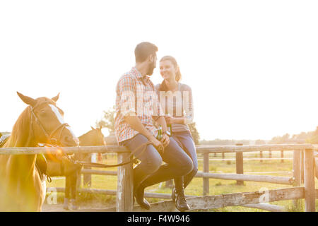 Couple avec horse en conversation sur pâturage Clôture rurale ensoleillée Banque D'Images