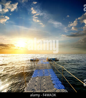 Ponton avec mains courantes dans la mer au coucher du soleil Banque D'Images