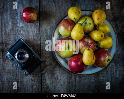 Appareil photo ancien, poires et pommes sur fond de vieillissement en bois Banque D'Images