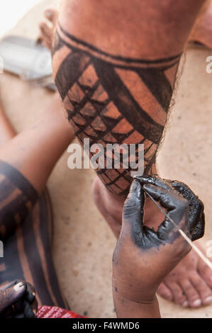 Palmas, Brésil. 22 octobre, 2015. Une femme Kayapo peint une jambe du visiteur avec black Genipapo peinture corps aux premiers Jeux autochtones de l'International, dans la ville de Palmas, Tocantins, Brésil l'État. Credit : Sue Cunningham/Photographique Alamy Live News Banque D'Images