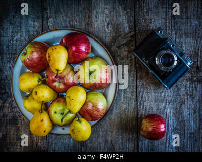 Appareil photo ancien, poires et pommes sur fond de vieillissement en bois Banque D'Images