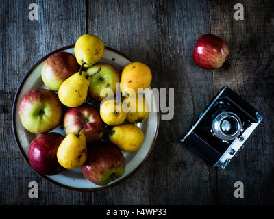 Appareil photo ancien, poires et pommes sur fond de vieillissement en bois Banque D'Images