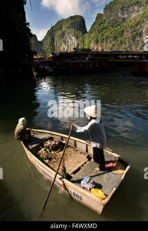 Un bateau d'aviron de femme, la collecte des ordures des bateaux de touristes, Halong Bay, Viet Nam. Un bateau à rames à travers la baie d'Halong, Vietnam. Port de Cat Ba Halong Bay golfe du Tonkin Vietnam Asie du Sud Est. Banque D'Images