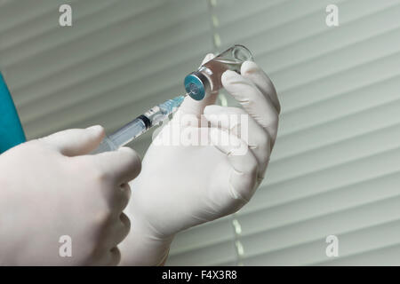 Attire l'infirmière la solution dans la seringue de flacon dans le bureau de la clinique. Banque D'Images